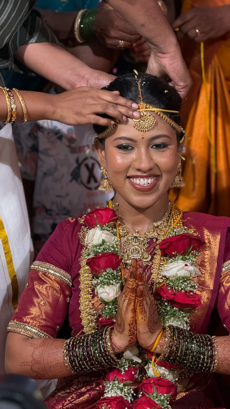 Smiling bride in red and green silk with flower garlands