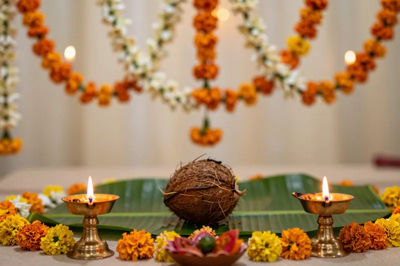 Concept image: marigold and jasmine garlands with brass oil lamps at a wedding mandapam