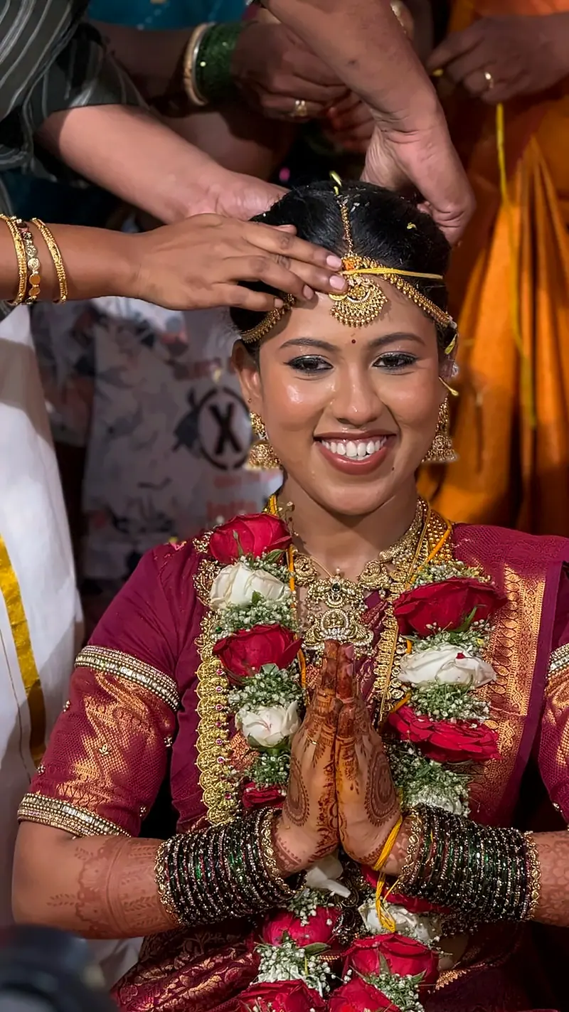 Smiling bride with flower garlands, folded hands