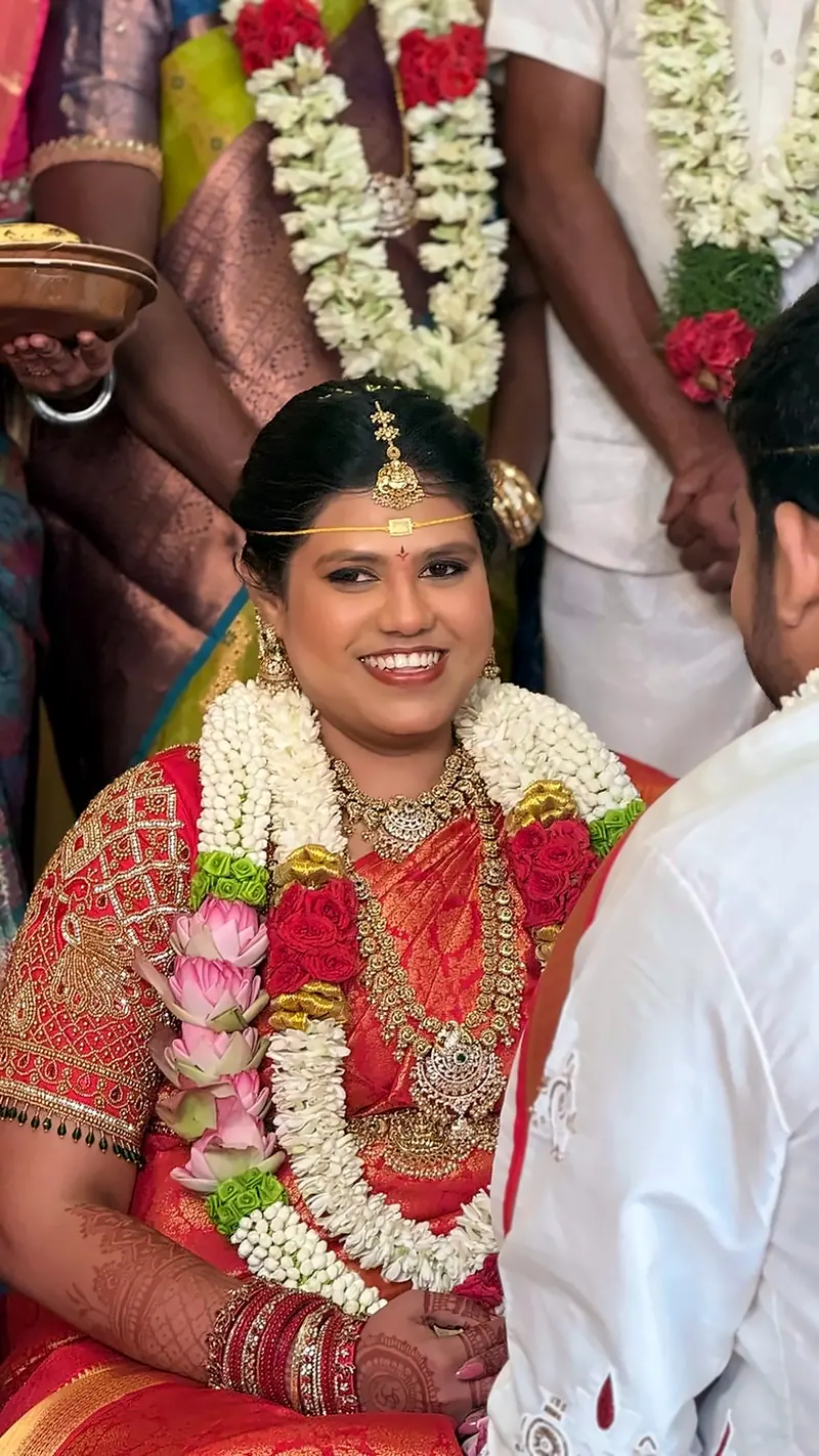 Bride in red silk saree with rose and jasmine garlands during the wedding ceremony