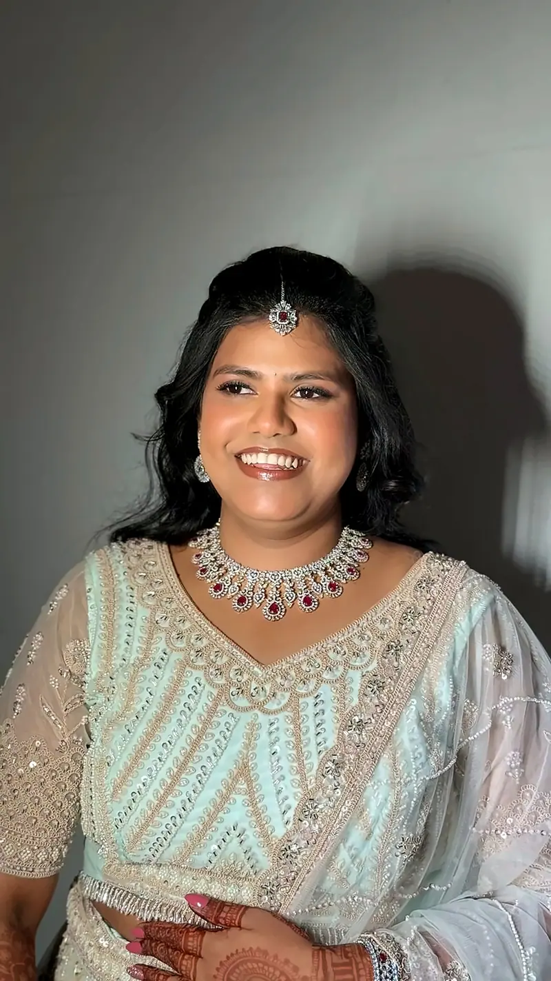 Smiling woman in a pastel embroidered outfit with maang tikka, reception and engagement makeup in Chennai
