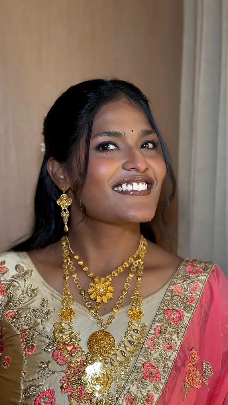 Smiling woman in a cream and pink outfit with gold jewellery