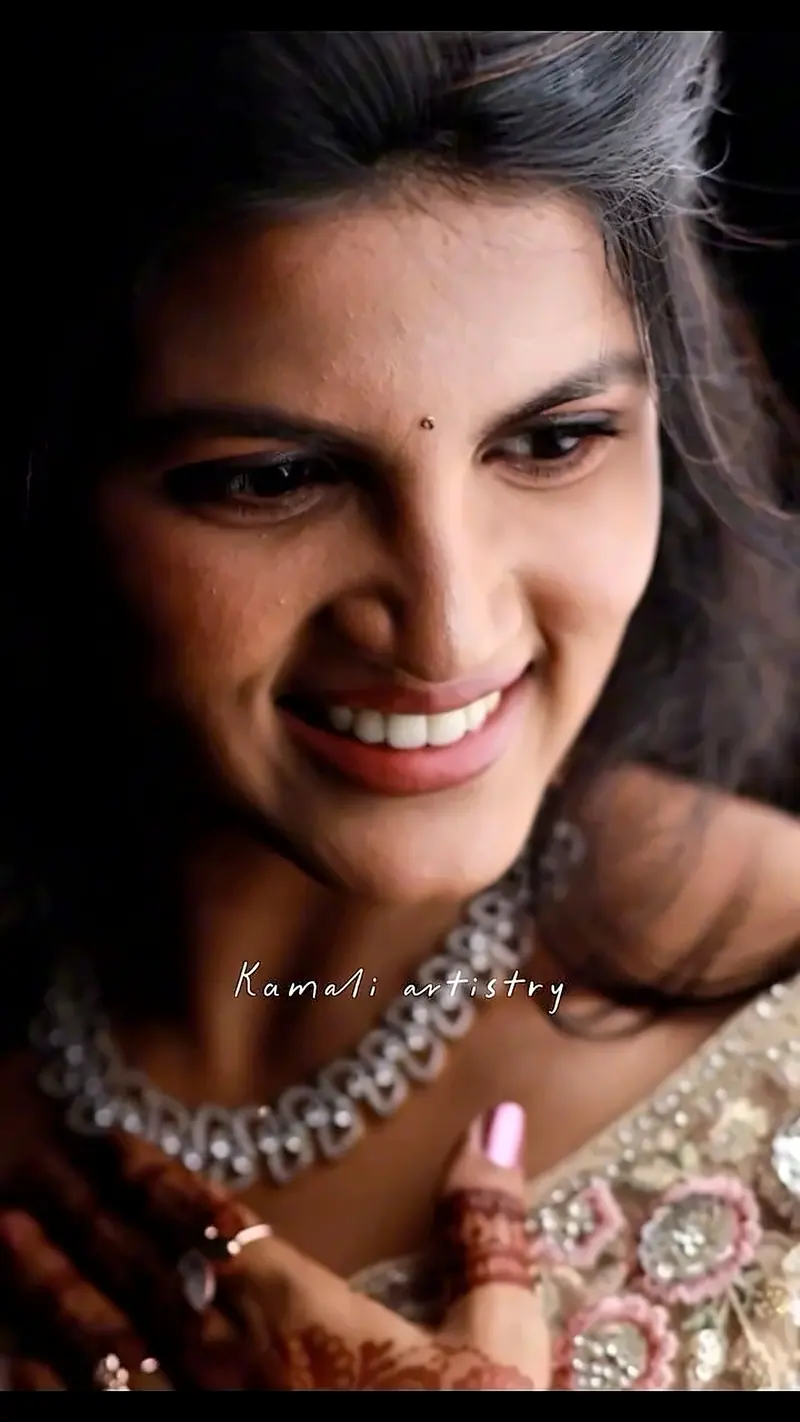 Close-up of a laughing bride with a diamond necklace and mehandi on her hands