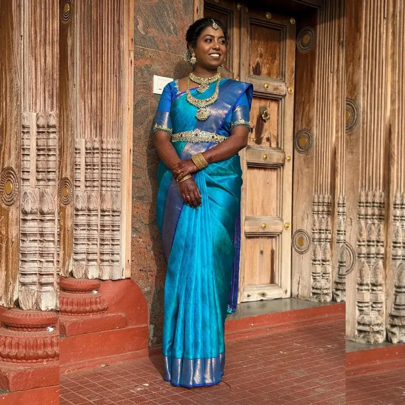 Woman in turquoise silk saree with gold border, neatly draped