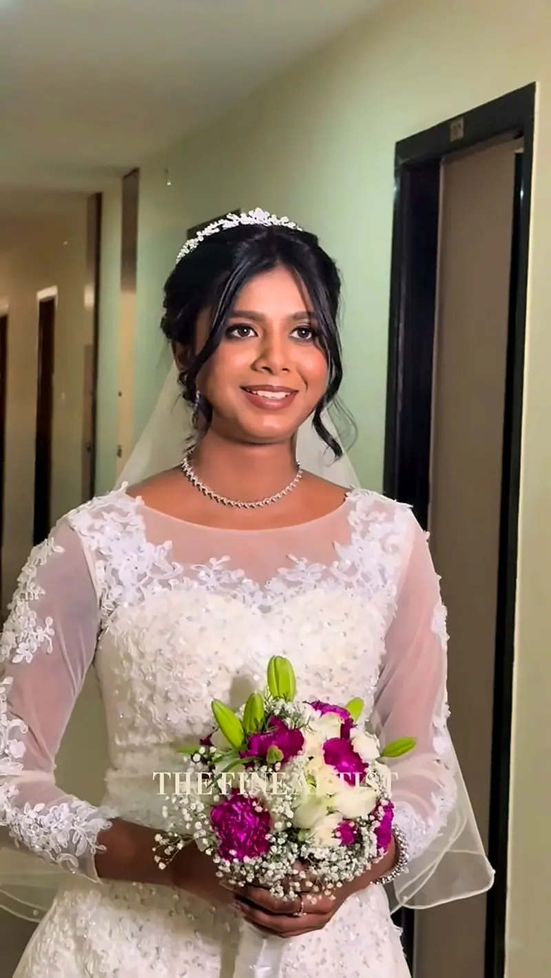 Bride in white lace gown with bouquet in a corridor