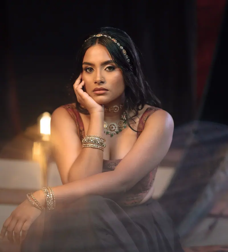 Moody editorial portrait of a woman with gold jewellery by candlelight, photoshoot makeup
