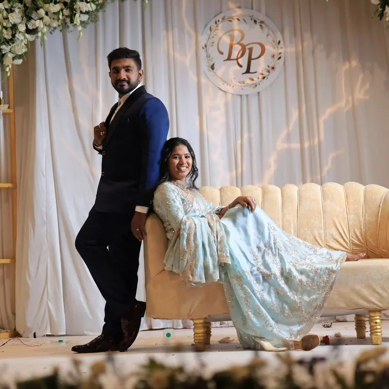 Couple posing on a sofa in front of an engagement backdrop