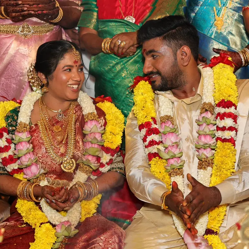 Couple seated in silk and flower garlands during a wedding ritual