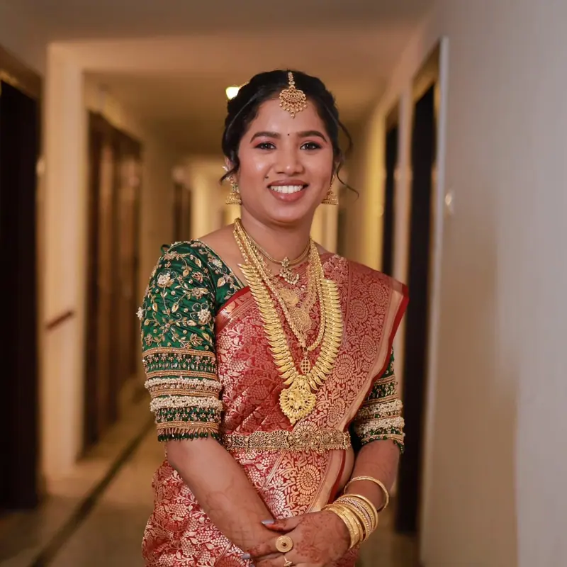 Smiling bride in green and red silk saree with gold bangles