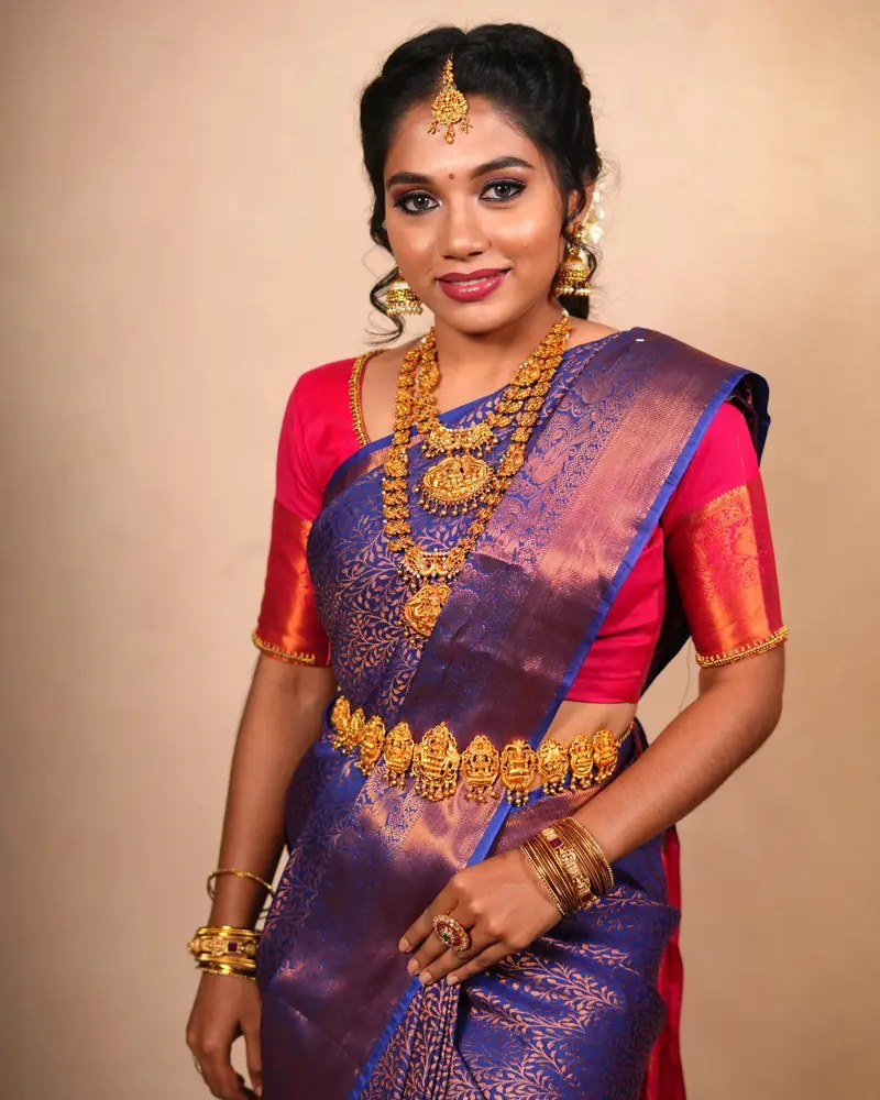 Bride in a purple and copper Kanjivaram silk saree with gold temple jewellery, studio portrait