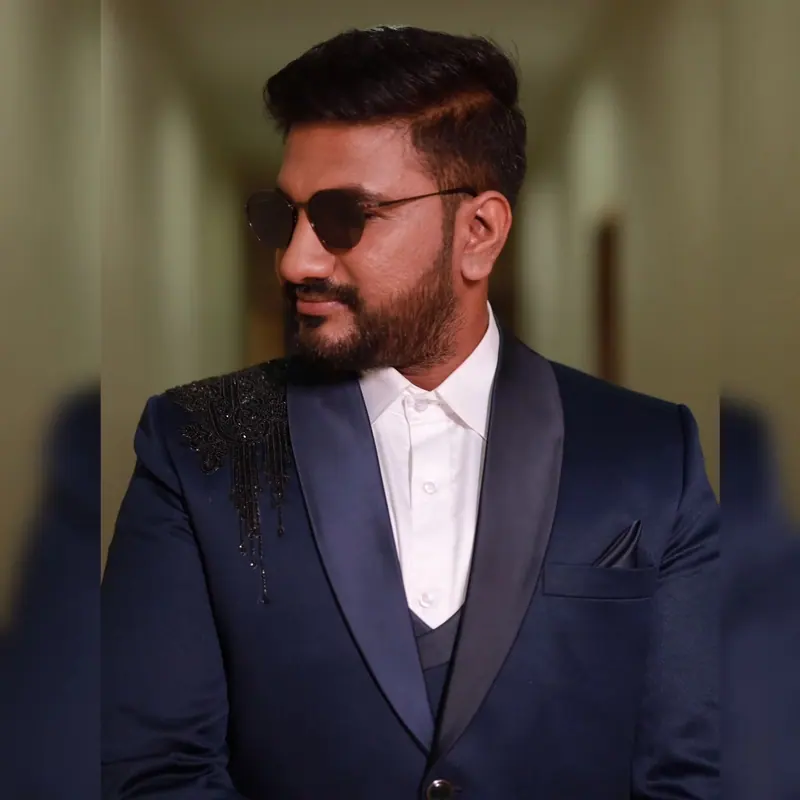Groom in a navy suit and sunglasses at the reception